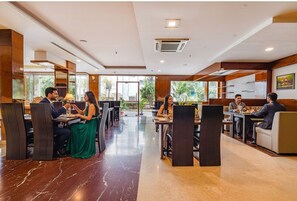 Un comedor moderno con suelo de mármol, paneles de madera y ventanas amplias que dan a zonas verdes.