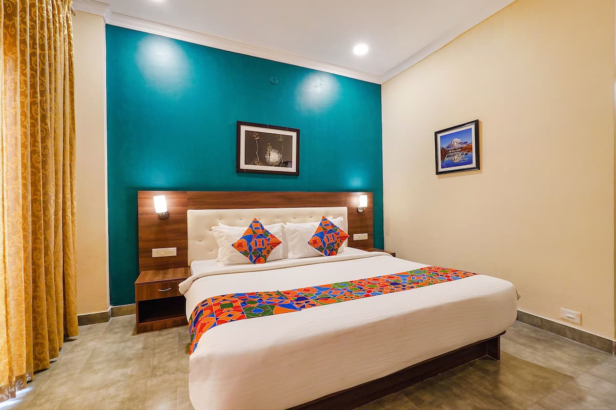 A hotel room with a bed, a nightstand, a wooden headboard, and two framed pictures on the walls.