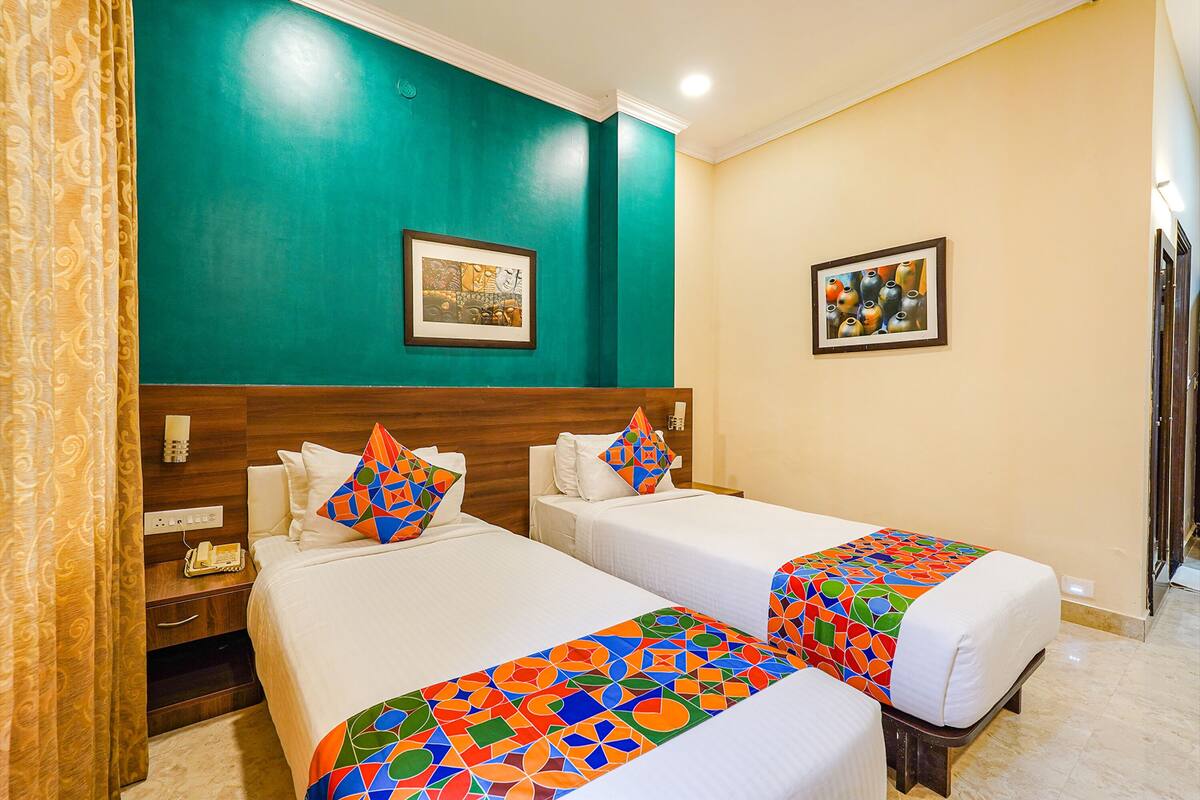 A hotel room with two beds, teal walls, and colorful bedspreads.
