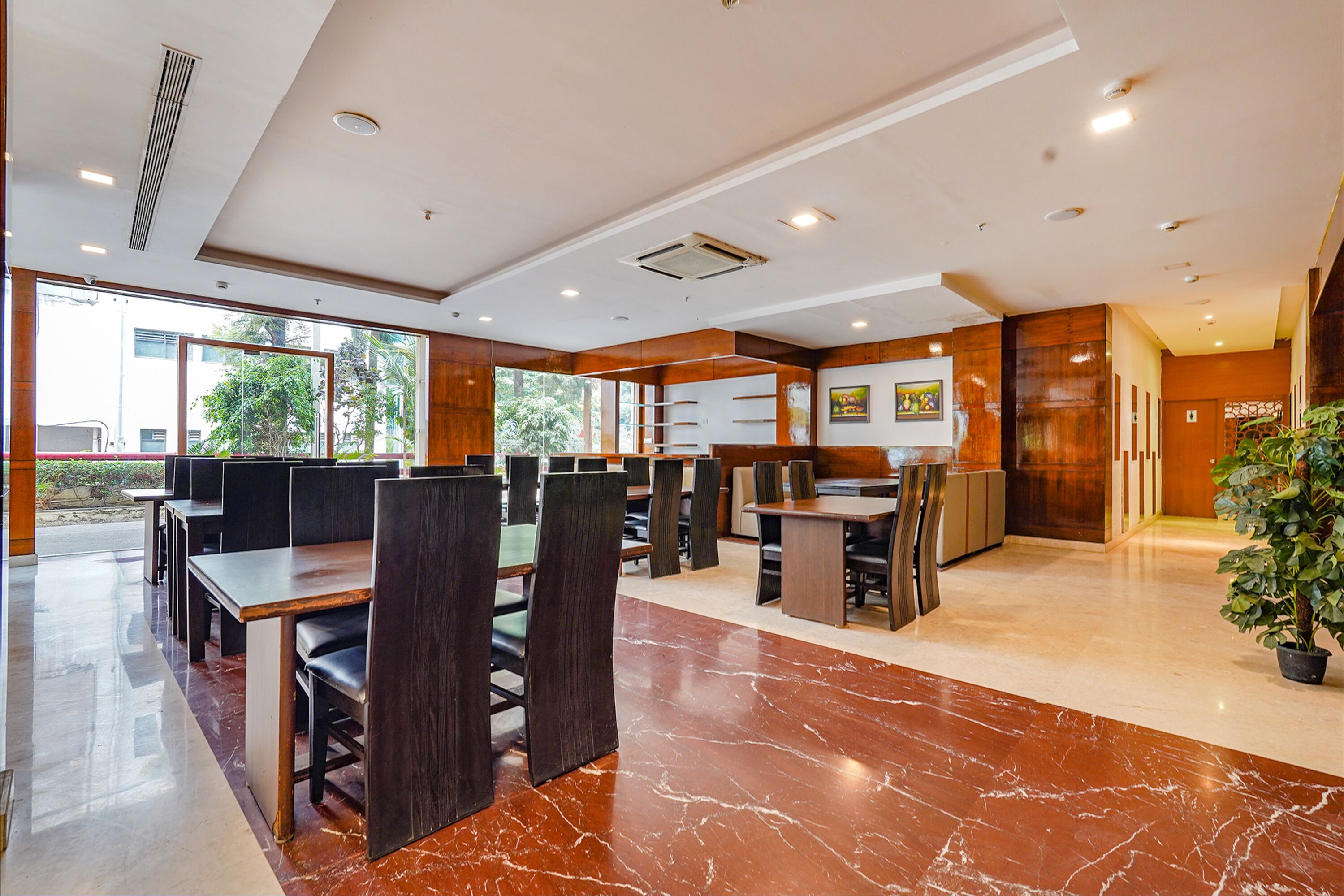 Un ristorante moderno con pavimento in marmo, arredi in legno e ampie finestre che offrono vista sull'esterno.