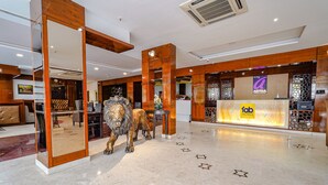 A hotel lobby with a reception desk, a large mirror, and a lion statue. - FabHotel Chris - Whitefield near KTPO & ITPL (Bengaluru)