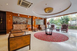 A lobby with a round red carpet, a tufted sofa, and a patterned wall. - FabHotel Chris - Whitefield near KTPO & ITPL (Bengaluru)