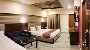 A hotel room with a large bed, a sofa, a small table, and a wardrobe. - Fabhotel Astra Berry'S (Bengaluru)