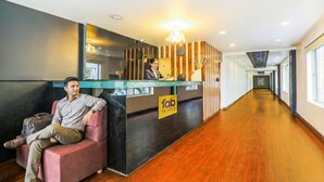 A hotel reception area with a modern design, including a reception desk, a seating area, and a corridor leading to other parts of the hotel. - Fabhotel Astra Berry'S (Bengaluru)