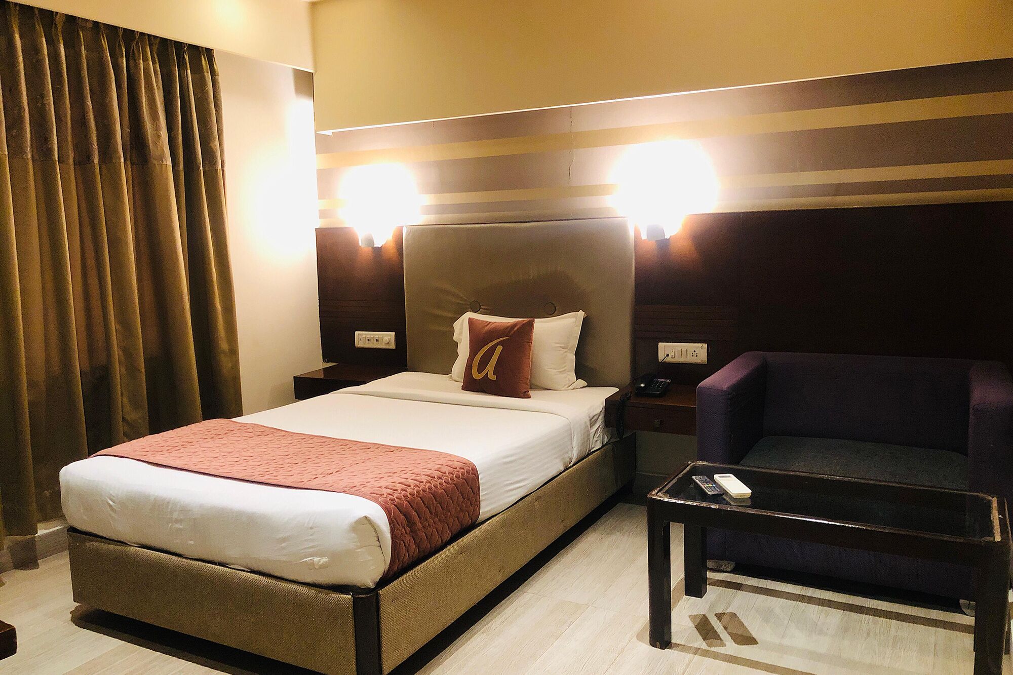A hotel room with a bed, a nightstand, a chair, and a lamp.