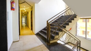 A modern hotel interior with a staircase, a fire extinguisher, and a view of the outside through a window. - FabHotel Prime Supreme Grande 600 Mtrs away from Calangute beach (Calangute)