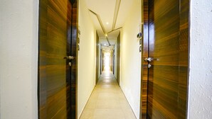 A long, narrow hallway with wooden doors on both sides and a tiled floor. - FabHotel Prime Supreme Grande 600 Mtrs away from Calangute beach (Calangute)