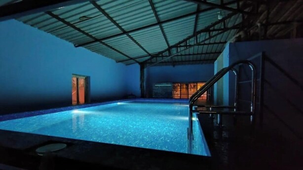 An indoor swimming pool with a metal roof and a door leading to another room. - FabHotel Prime Supreme Grande 600 Mtrs away from Calangute beach (Calangute)