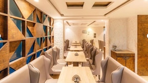 A restaurant interior with a modern design, featuring geometric wooden panels, cushioned seating, and a clean, well-lit ambiance. - FabHotel Prime Supreme Grande 600 Mtrs away from Calangute beach (Calangute)