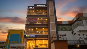 Un edificio de hotel de varios pisos con un letrero que indica 'J.M.S TOWER' y 'fabHOTELS' en la planta baja.