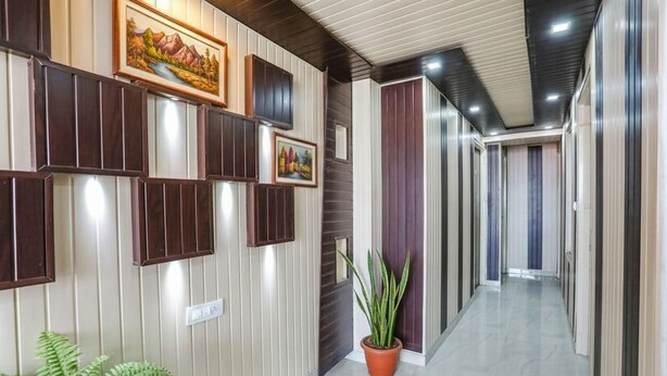 Un pasillo de diseño moderno, con paneles de madera y metal, una planta en maceta y cuadros en las paredes.