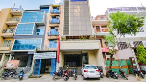 A multi-story building with a 'Tab Hotels' sign, a visible entrance, and several parked motorcycles and cars. - Fabexpress The Divine Residency (New Delhi)