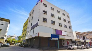 A multi-story hotel with a flat facade, air conditioning units, and a sign indicating it is the Golden Wings Hotel. - Fabexpress Golden Wings (Udaipur)