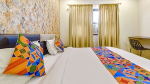 A hotel room with a bed, a desk, and a window with curtains. - Fabexpress Golden Wings (Udaipur)