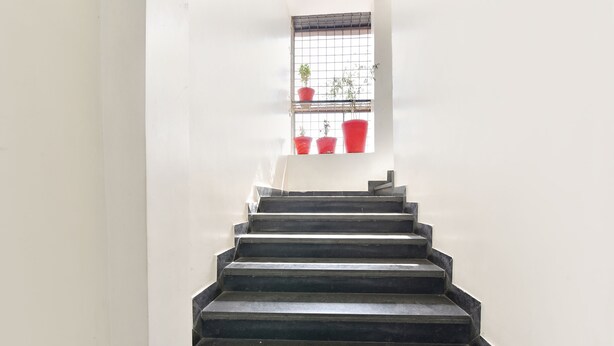 A staircase leading to a landing with a window above. - Fabexpress Golden Wings (Udaipur)