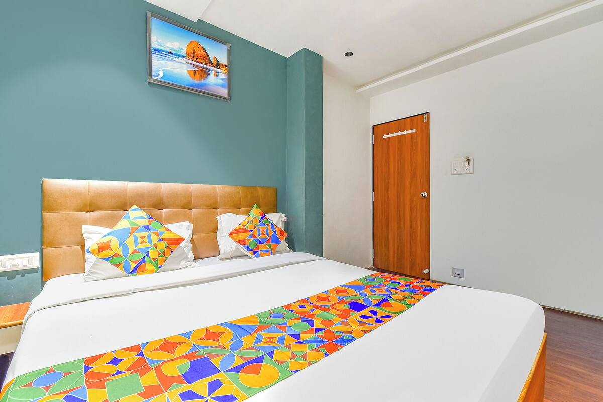 A bedroom with a large bed, a wooden door, and a painting on the wall.