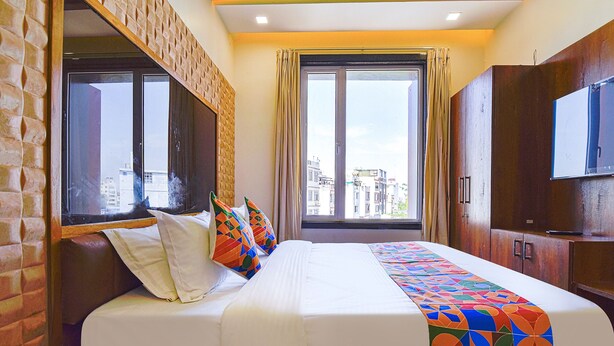 Una camera d'hotel con un letto grande, una televisione e una finestra vista città.