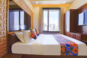 A hotel room with a large bed, a TV, and a window with a city view. - Fabhotel Shree Ji (Udaipur)