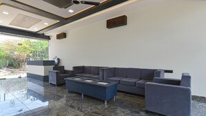 Una hall moderna con un divano dai colori scuri, un tavolino in vetro e una ventola a soffitto.