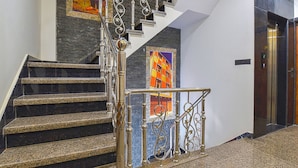 Una scala con ringhiera in metallo, un quadro appeso al muro e un ascensore.