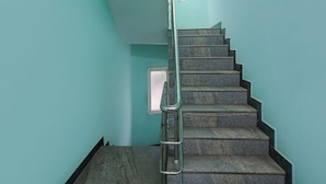 A staircase with metal handrails and stone steps, leading to a landing with a window. - Fabexpress Joel Inn (Chennai)