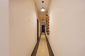 A narrow hallway with a polished floor, a hanging pendant light, and a patterned wall decoration.