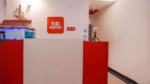 A reception desk with a 'Fab Express' sign, a QR code, and a camera on a tripod. - Fabexpress Joel Inn (Chennai)