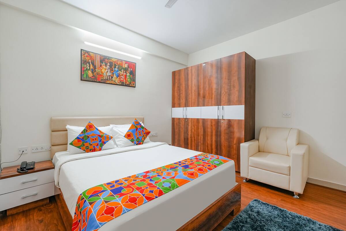 A bedroom with a bed, a wardrobe, a chair, and a painting on the wall.