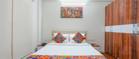 Una habitación de hotel con cama, mesita de noche, armario y un cuadro en la pared.