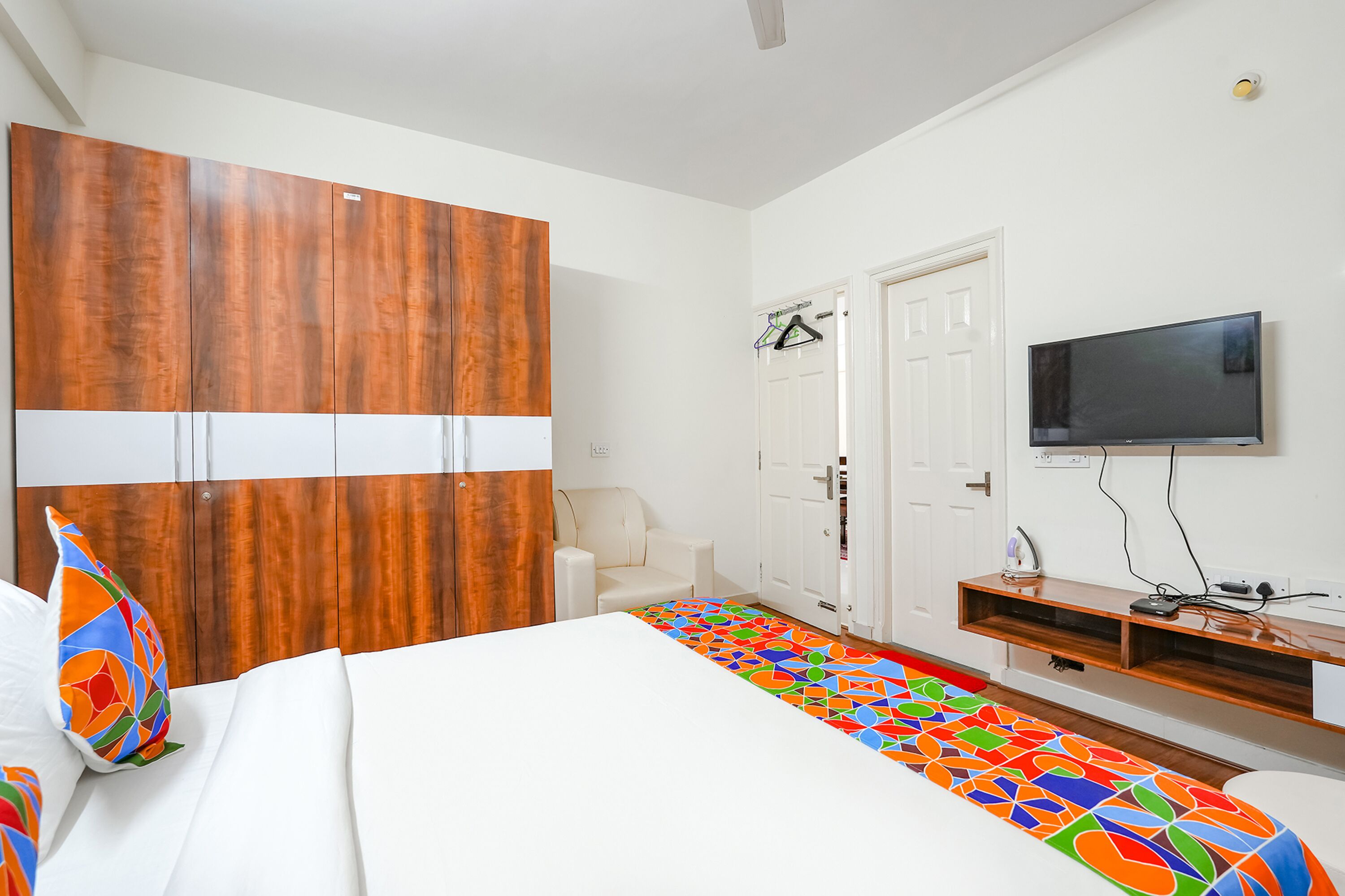 Une chambre à coucher avec un lit, une armoire, un téléviseur et un tapis coloré.