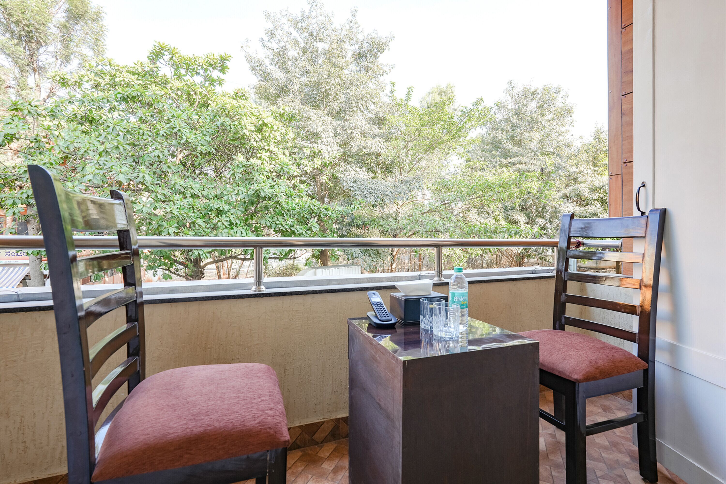 Ein Balkon mit zwei Stühlen, einem Tisch und einer Wasserflasche.