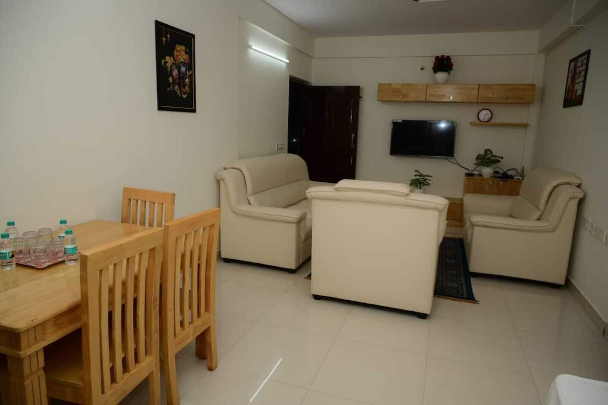 A living room with a wooden dining table, two beige sofas, a TV, and a wooden cabinet.