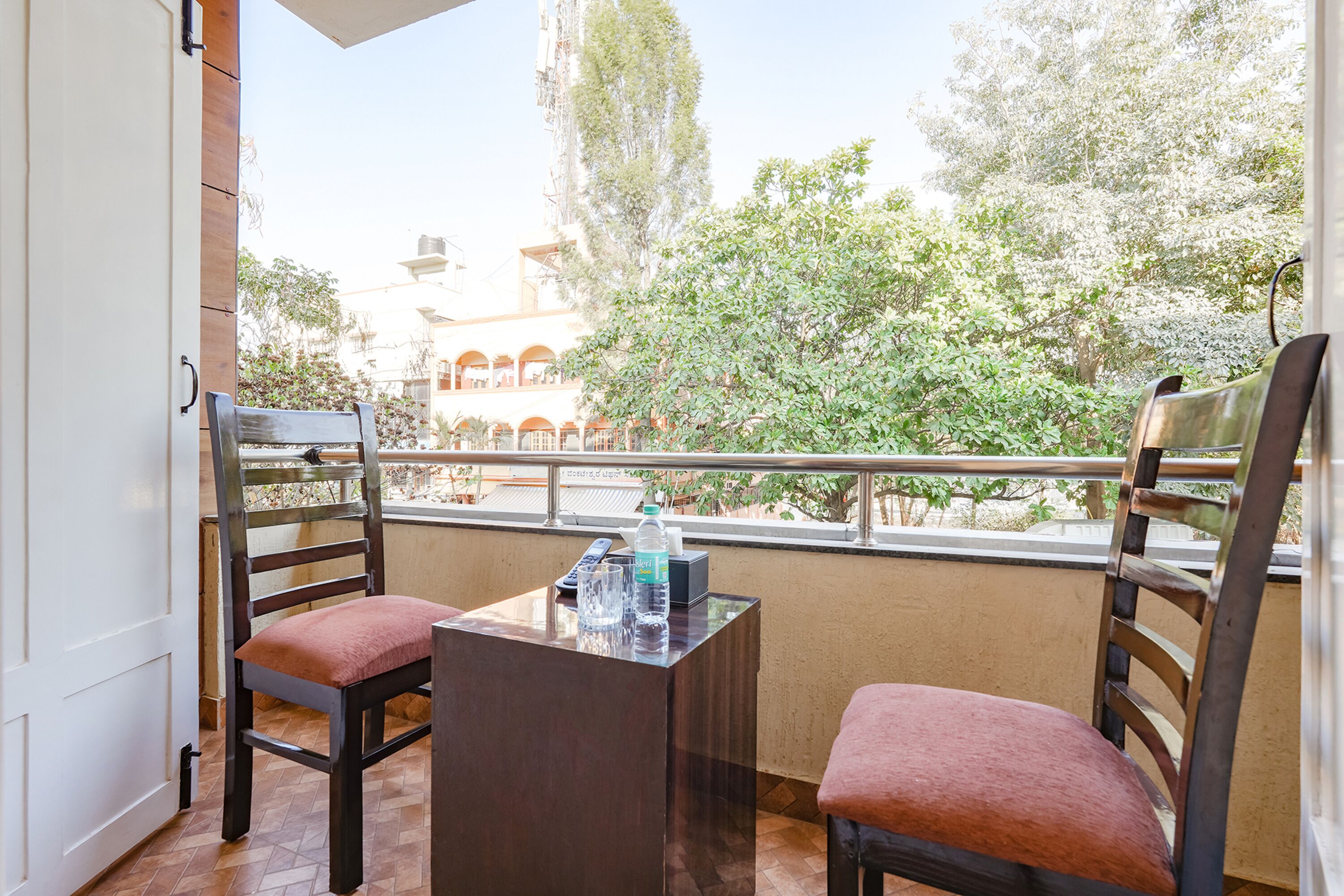 A balcony with two wooden chairs and a small table, a bottle of water, and a tissue box.