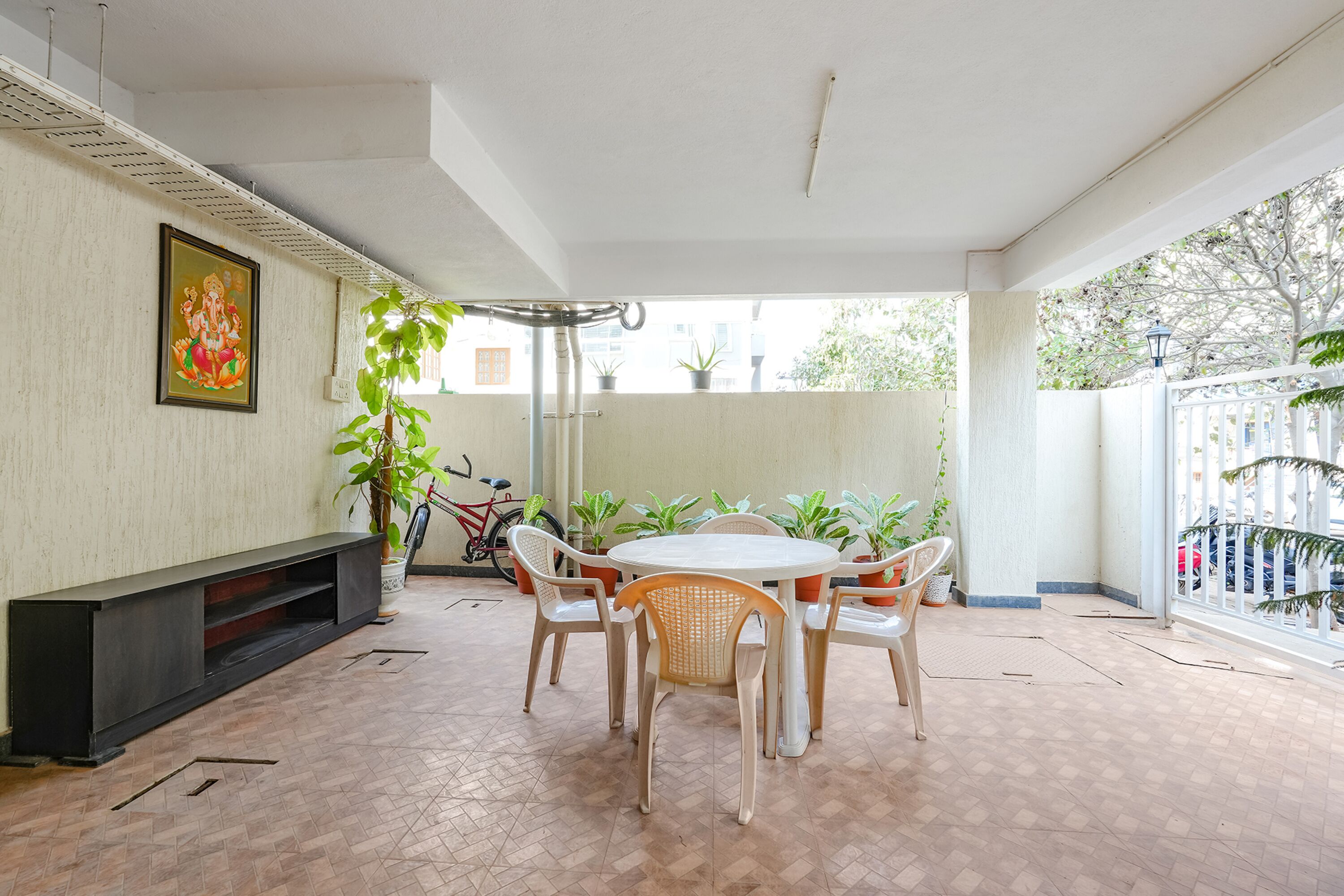 A spacious patio with a round table and chairs, surrounded by potted plants and a bicycle.