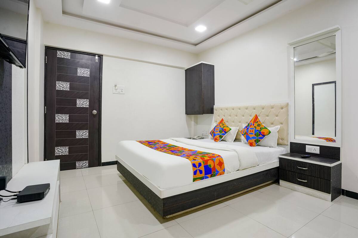 A modern bedroom with a bed, bedside tables, a dresser, a mirror, and a door.