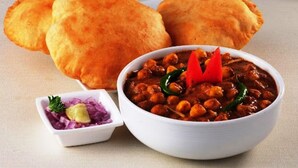 A bowl of chickpea curry with a side of sliced onions and a small bowl of chutney. - Fabhotel Elite Palm (Nagpur)