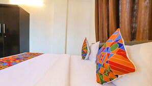 A hotel room with a bed, pillows, and a wardrobe. - Fabhotel Elite Palm (Nagpur)