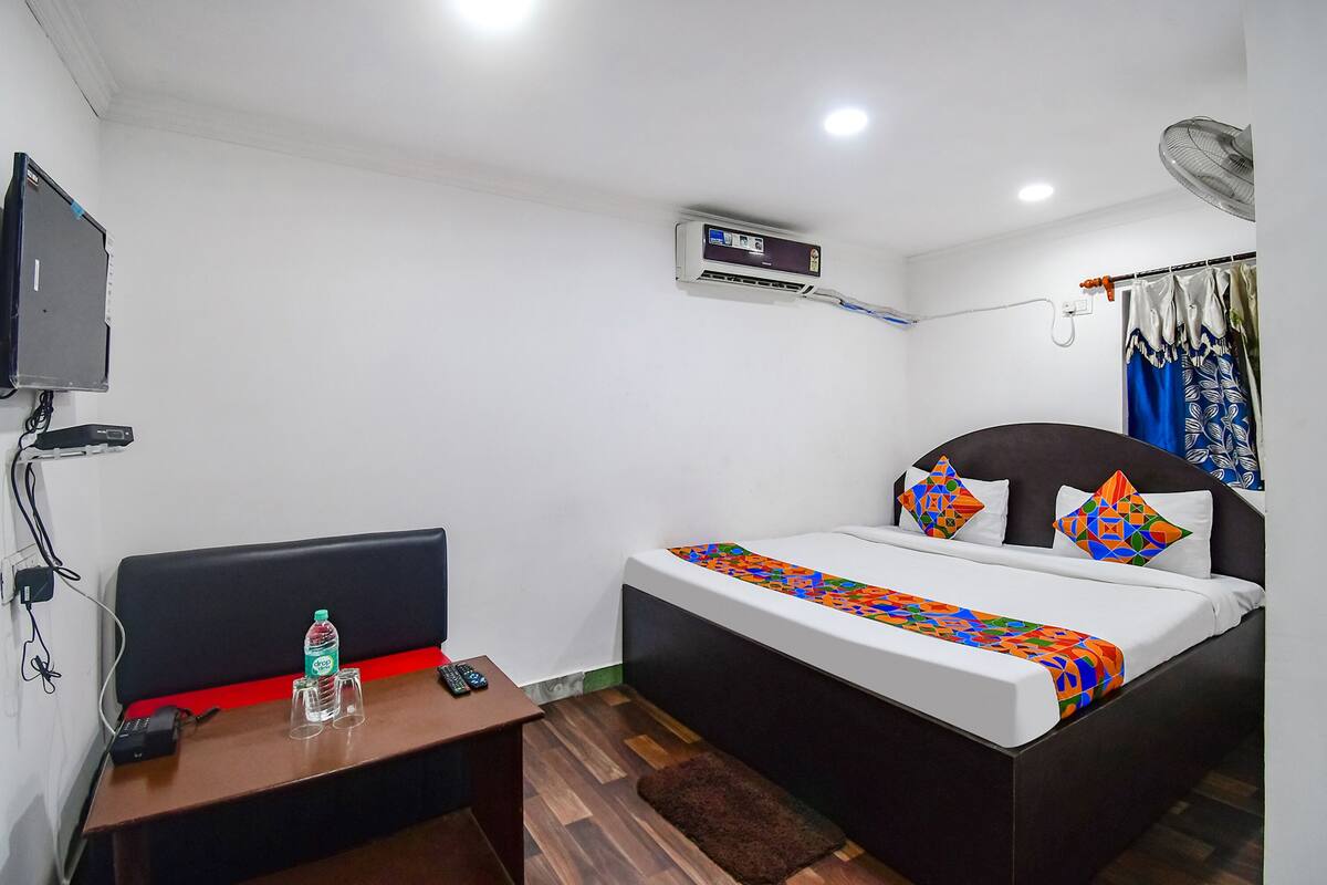 A bedroom with a bed, bedside table, and a wall-mounted air conditioner.