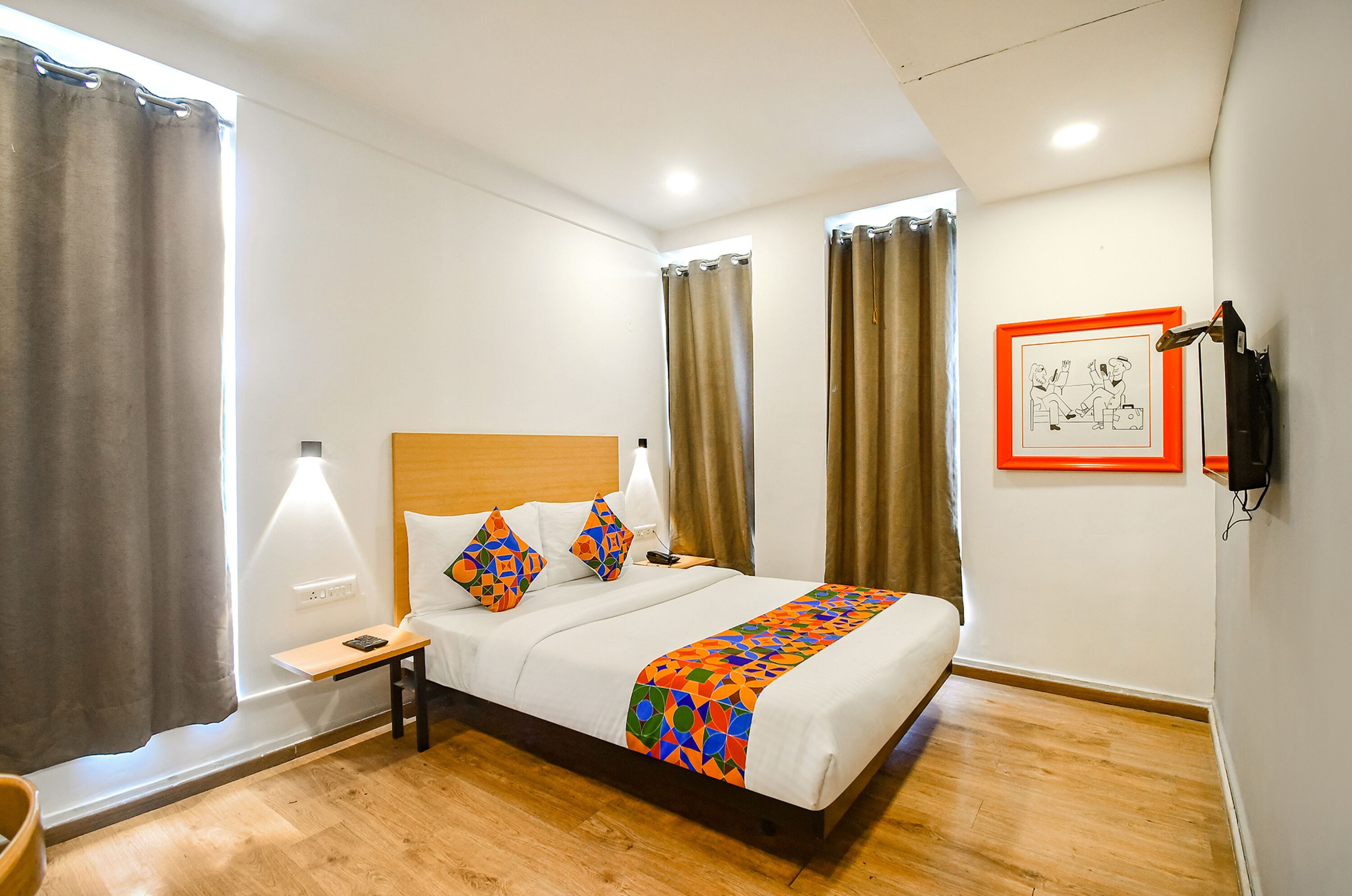 Una habitación de hotel con cama, mesita de noche, lámpara y un cuadro en la pared.