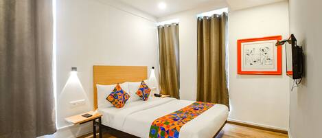 Una habitación de hotel con cama, mesita de noche, lámpara y un cuadro en la pared.