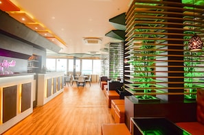 A modern restaurant interior with a bar area, seating, and green-lit plant displays.