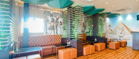 A modern interior with a seating area, wooden flooring, and decorative green elements.