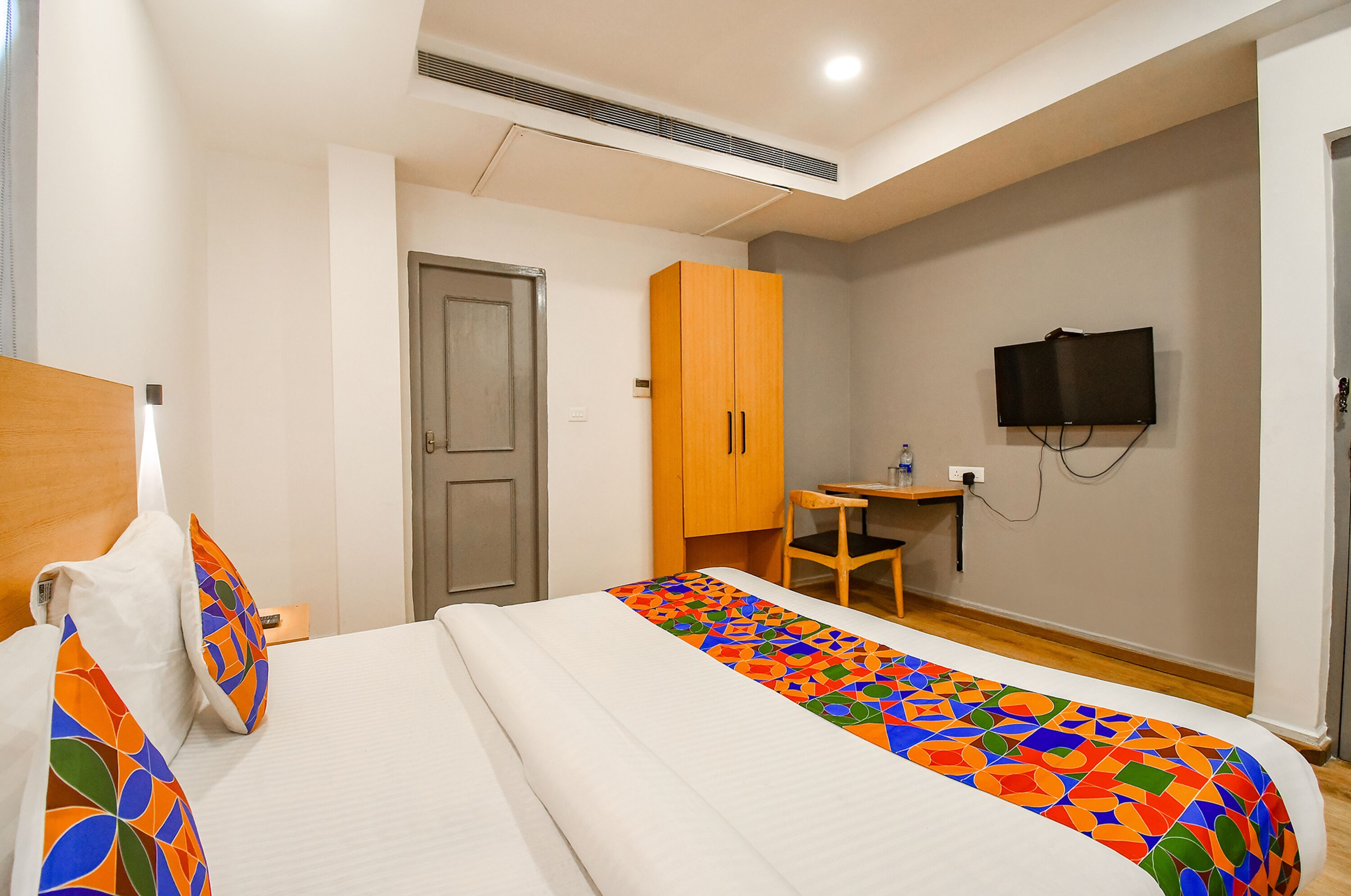 A hotel room with a bed, a desk, a television, and a wardrobe.