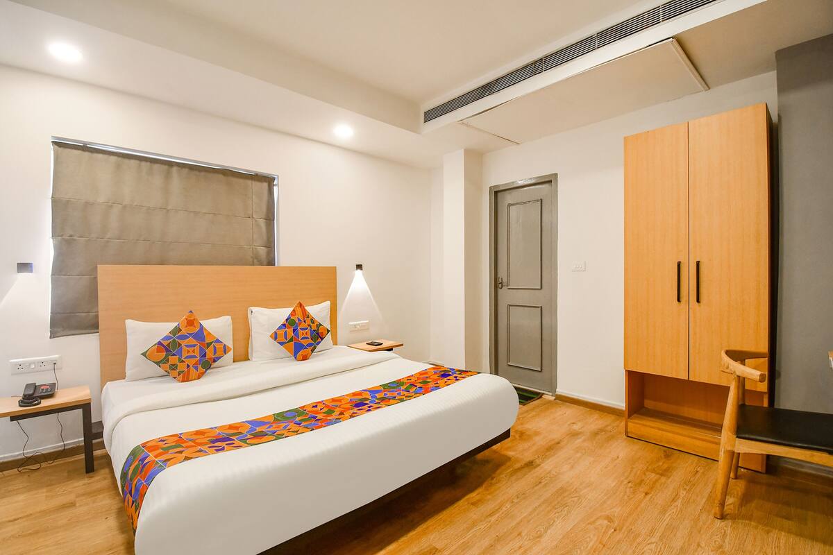 Een hotelkamer met een bed, nachtkastje, lamp, kledingkast en een stoel.