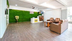A modern hotel lobby with a reception desk, seating area, and green wall. - Fabhotel Skylight Studio Rooms (Pune)