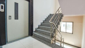 A staircase with metal railings and a door with a window and a small vent. - Fabhotel Skylight Studio Rooms (Pune)