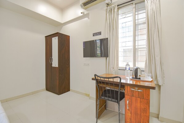A room with a wooden desk, a chair, a television, and a wardrobe. - Fabhotel Skylight Studio Rooms (Pune)