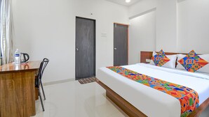 A hotel room with a bed, a desk, and a chair. - Fabhotel Skylight Studio Rooms (Pune)