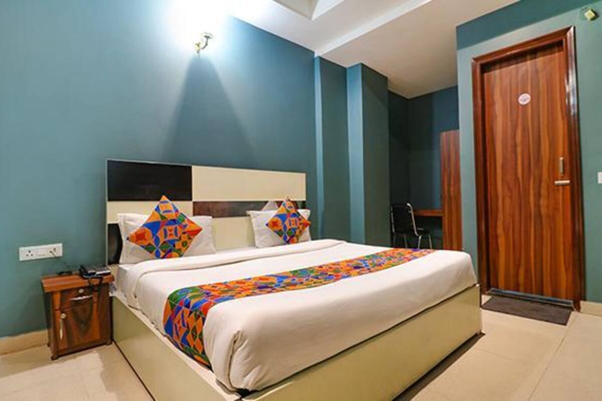 Una cama bien hecha con un edredón colorido, una mesita de noche de madera y una puerta de madera.