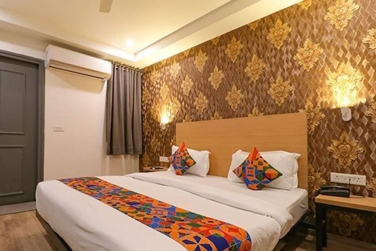 A hotel room with a bed, a nightstand, a lamp, and a door.